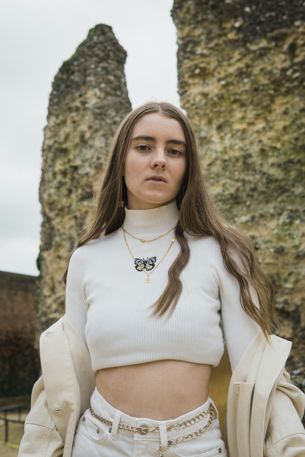 woman in white turtleneck sweater standing beside brown tree during daytime