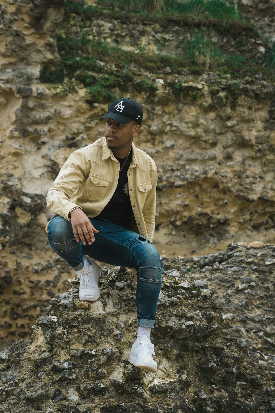 woman in blue denim jeans and brown jacket sitting on rock