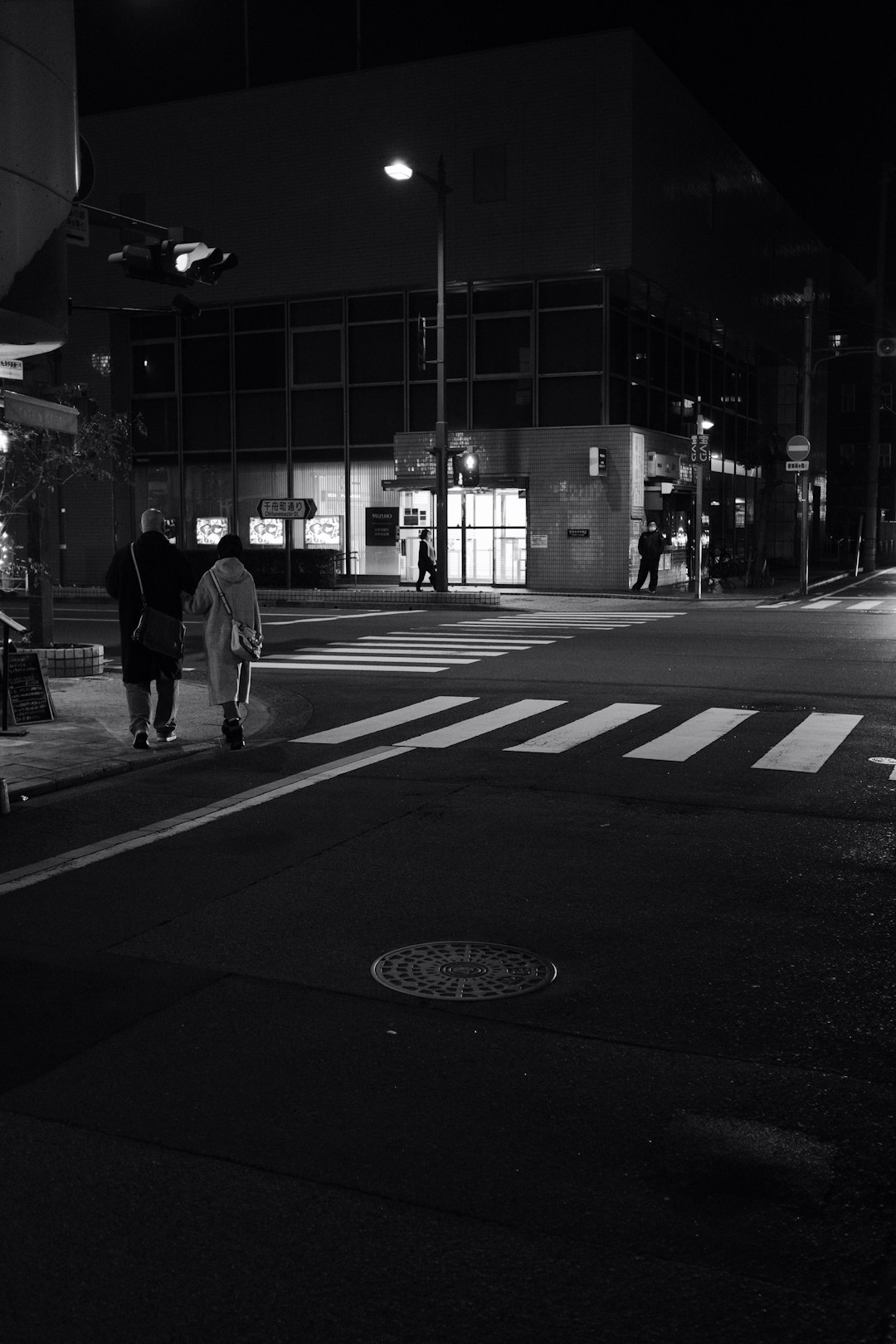 man in white long sleeve shirt walking on pedestrian lane during night time