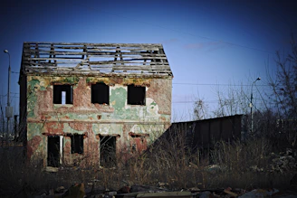 Exterior of a small house with damaged roof and cracked walls, ready for repair.