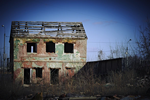 Exterior of a small house with damaged roof and cracked walls, ready for repair.