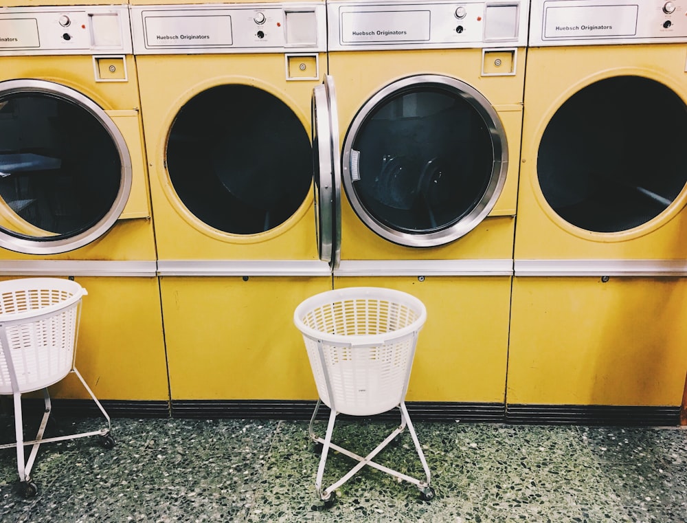 黄色のフロントロード洗濯機の横にある白いプラスチック製の洗濯かご