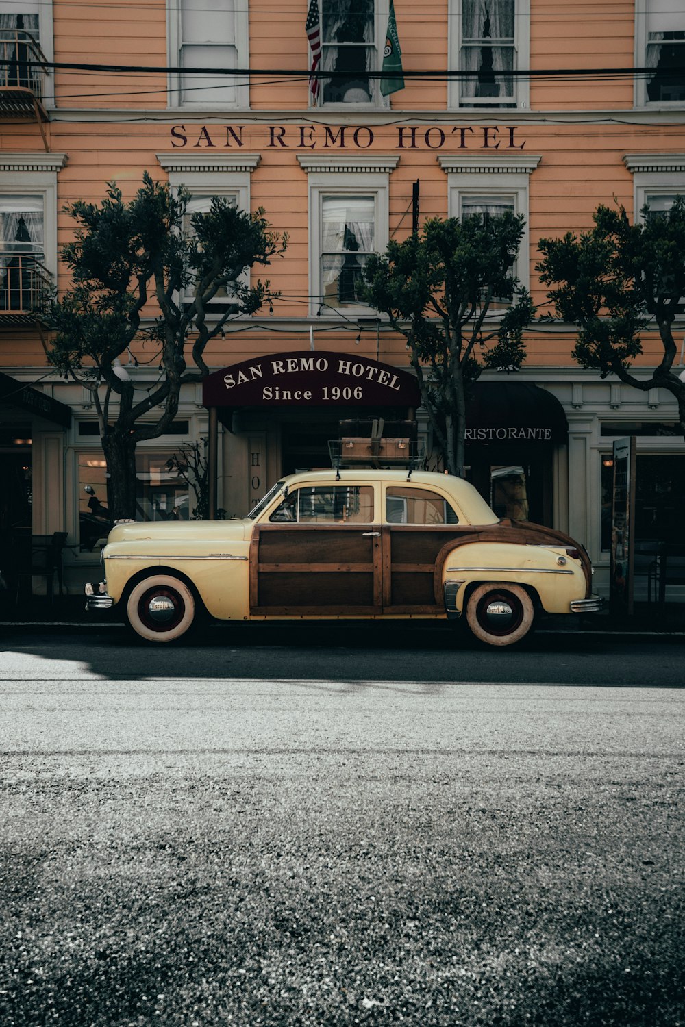 beige and white vintage car parked beside white concrete building during daytime