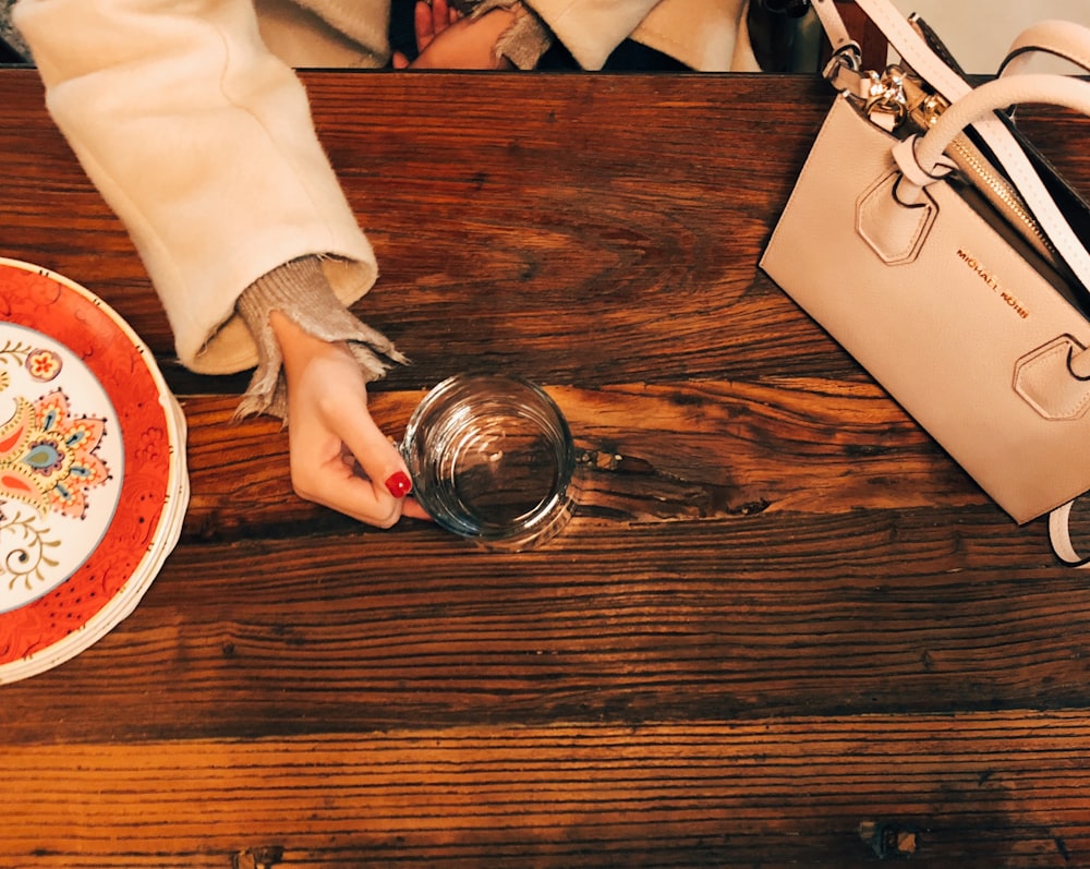 person in white long sleeve shirt holding clear drinking glass