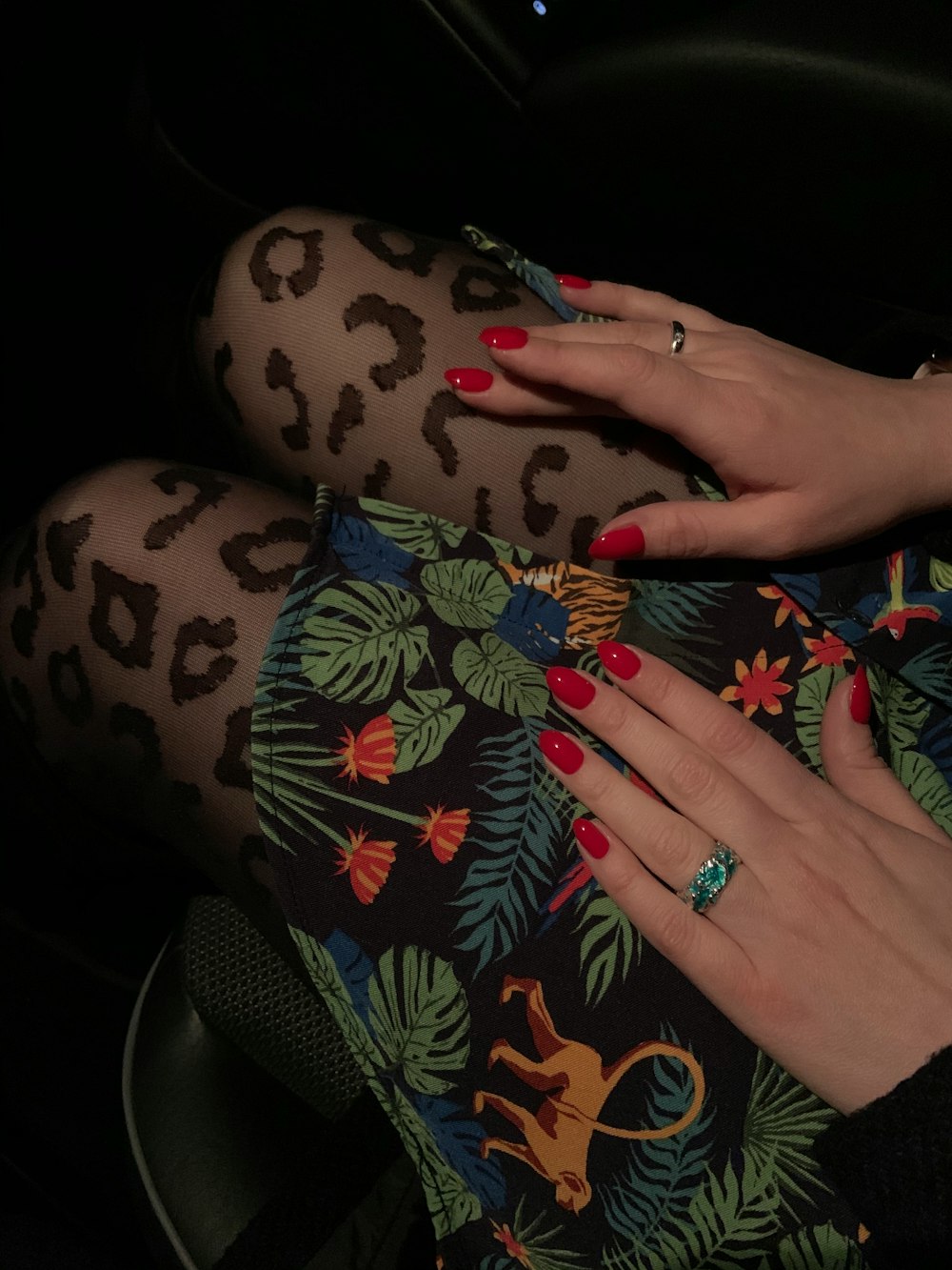 person wearing silver ring and black red and green floral pants
