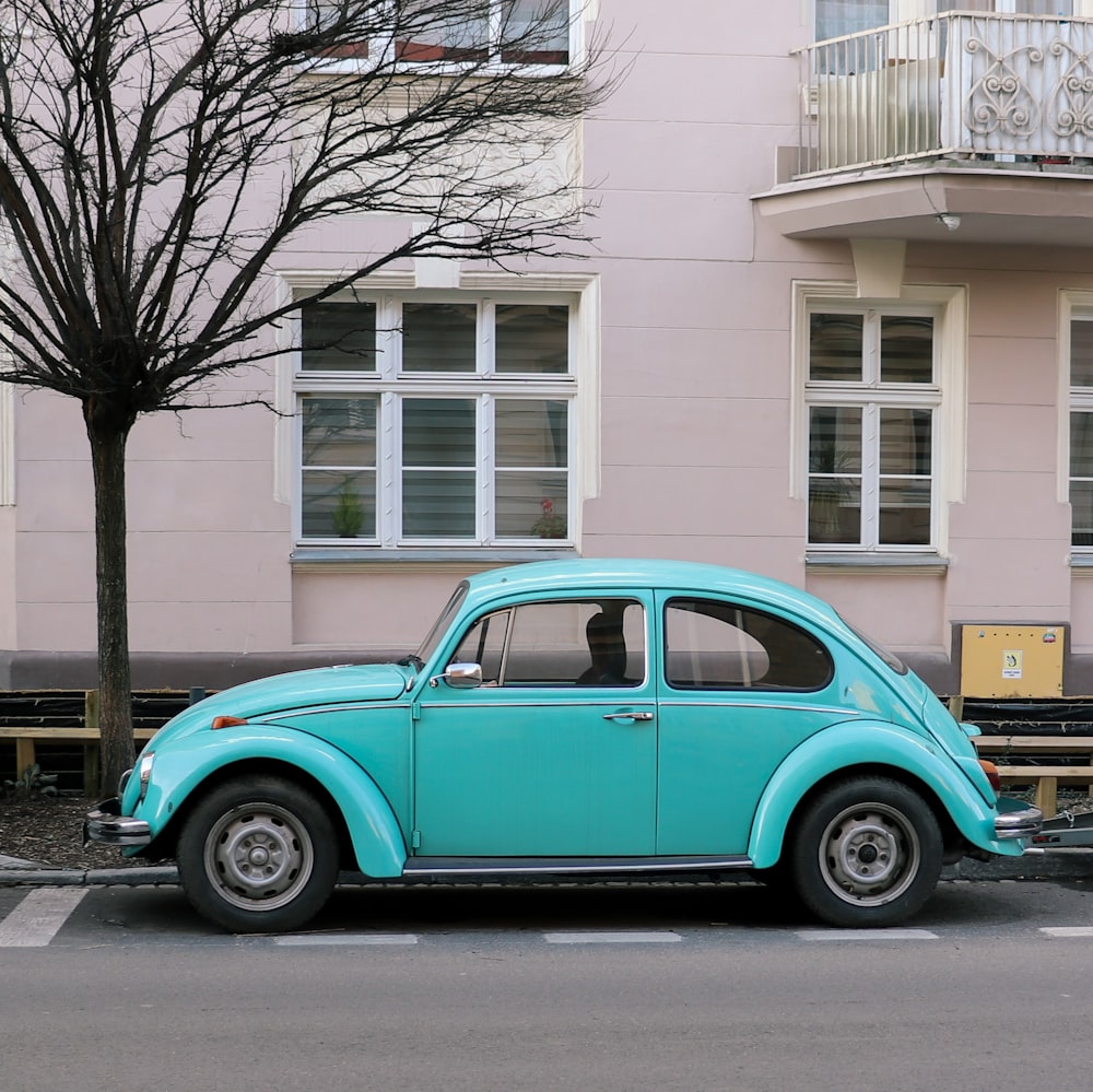 blue car parked beside brown concrete building during daytime