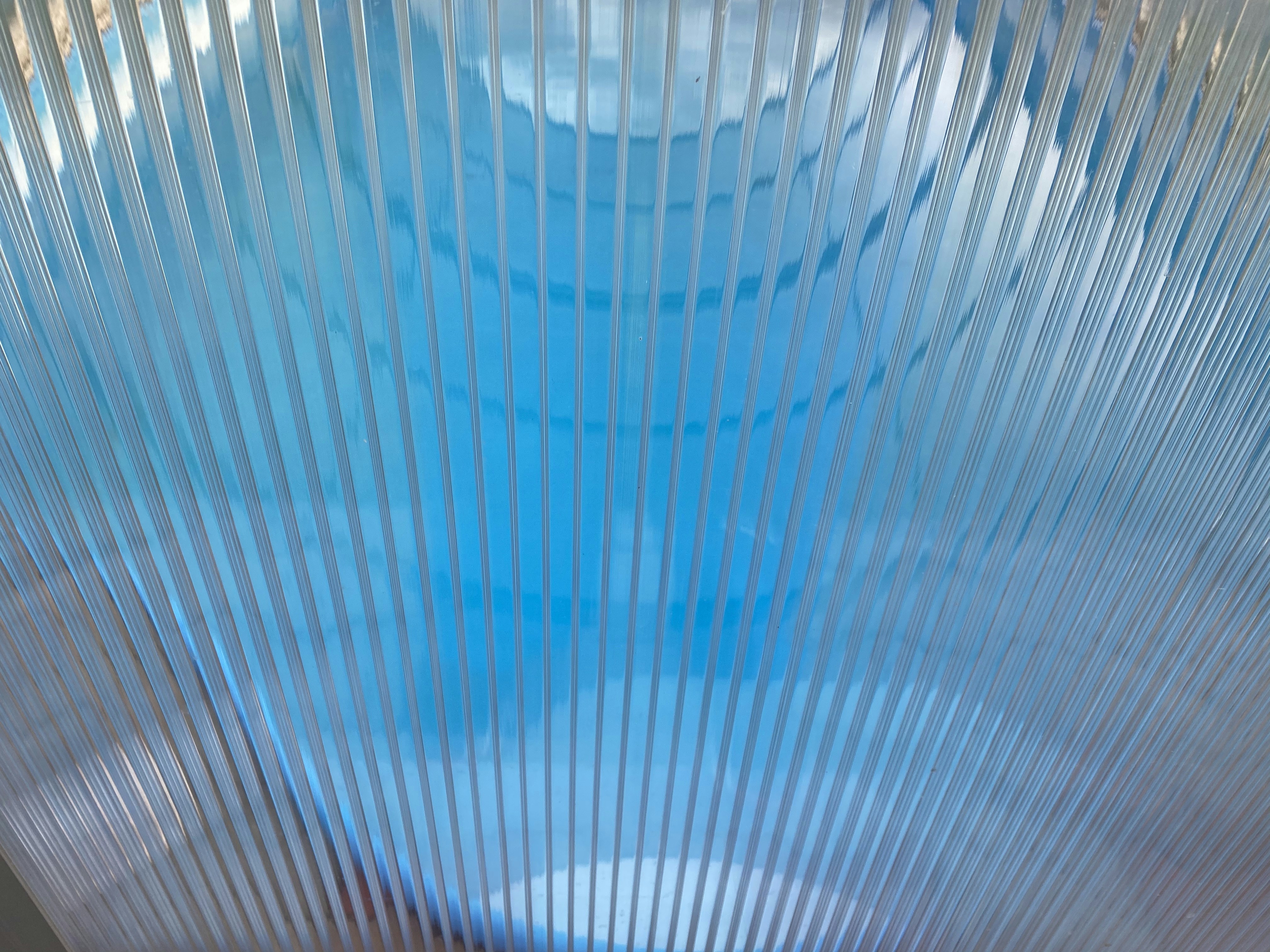 Transparent polycarbonate panels in an industrial facility, dramatic low-angle lighting, cool grey environment