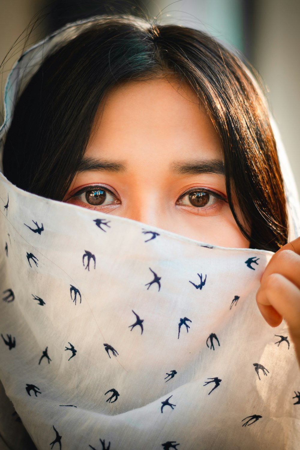 woman covering her face with white and black butterfly print textile