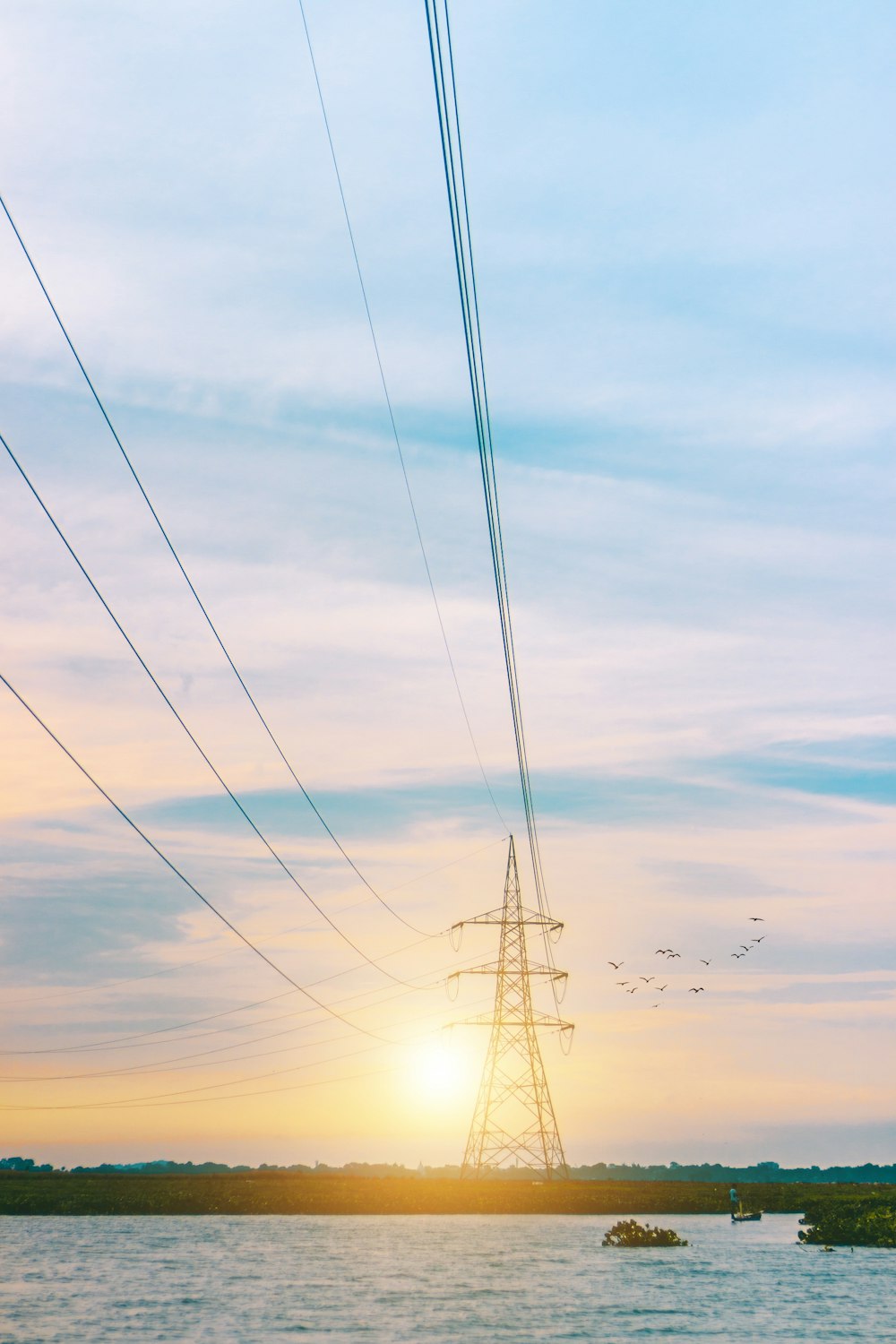 Silhouette des elektrischen Pfostens unter bewölktem Himmel bei Sonnenuntergang