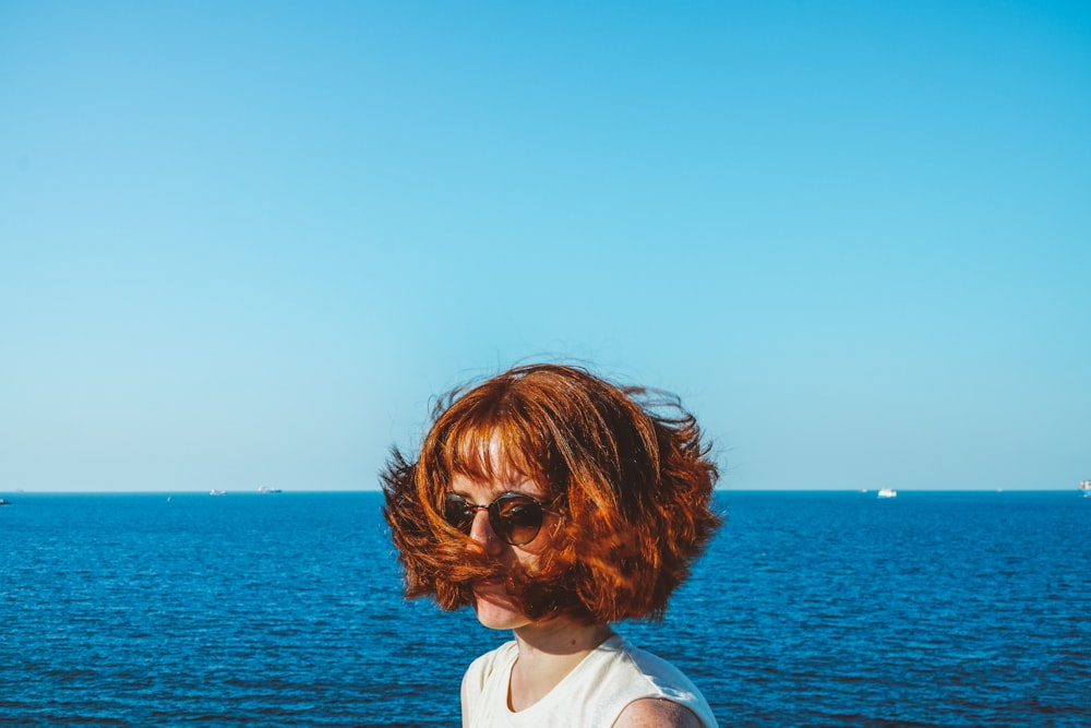 woman in white shirt looking at the sea during daytime