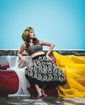 woman in black and white floral dress sitting on white bed
