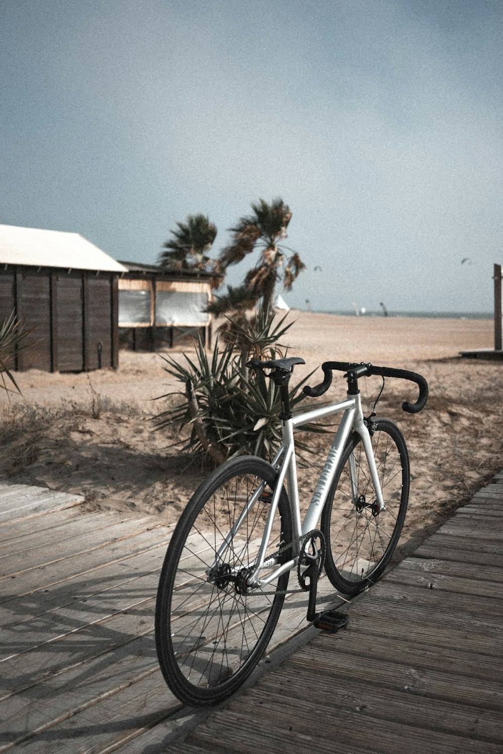 white and black road bike parked on brown wooden pathway during daytime