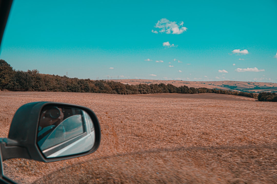 car on brown field under blue sky during daytime