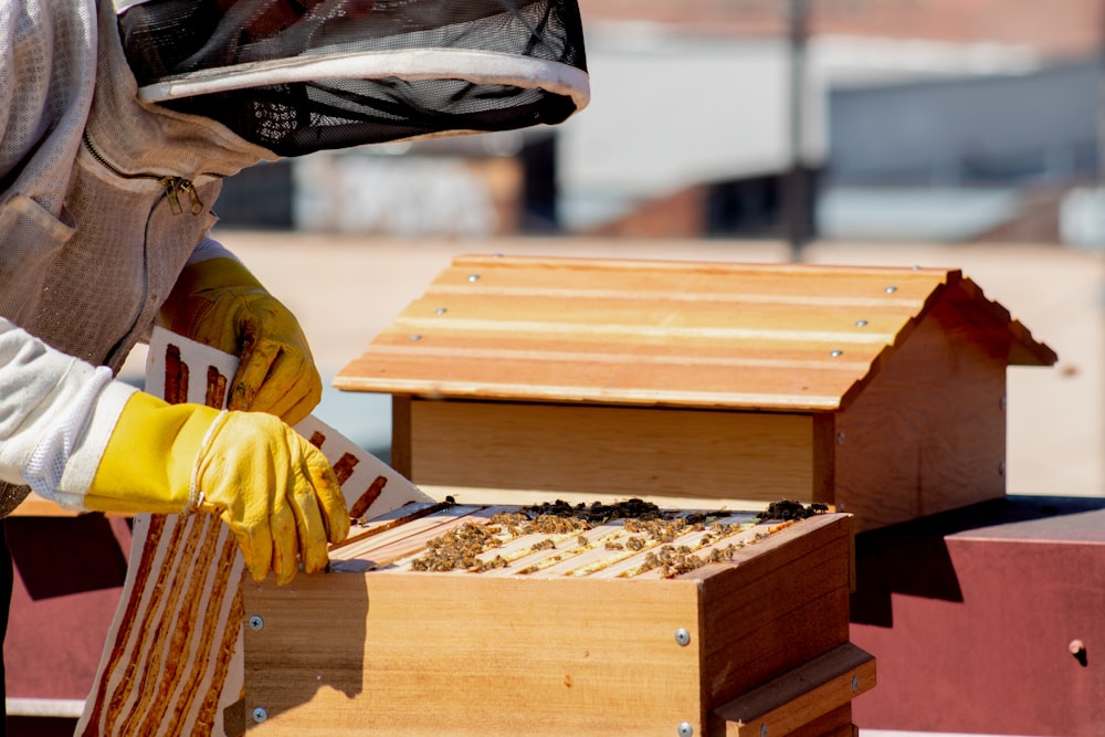 person in yellow jacket holding brown wooden box