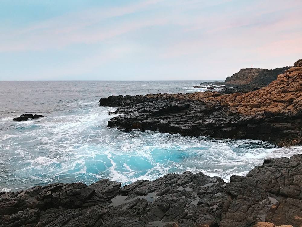 brown rock formation beside body of water during daytime