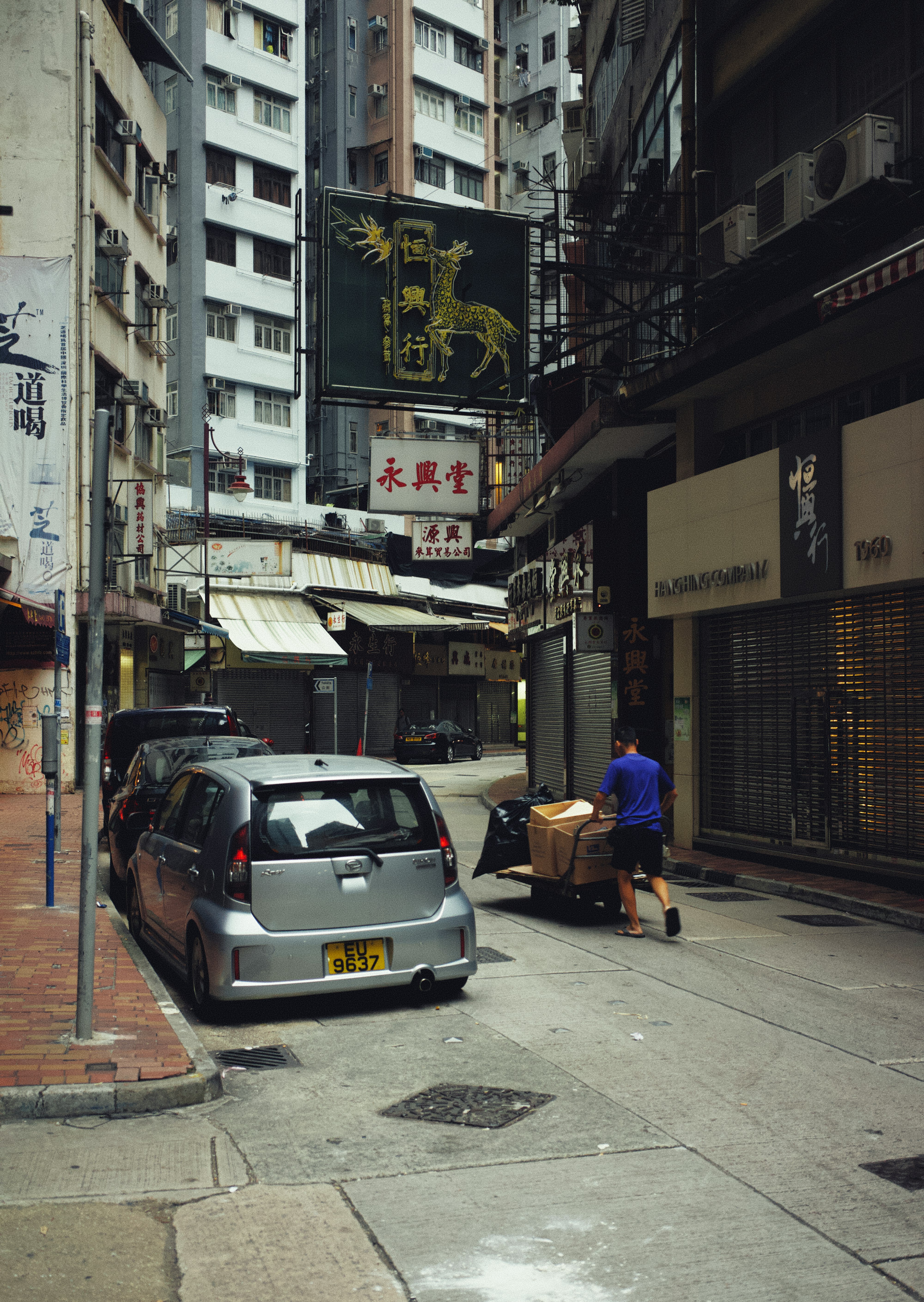 man in blue jacket standing beside white car during daytime