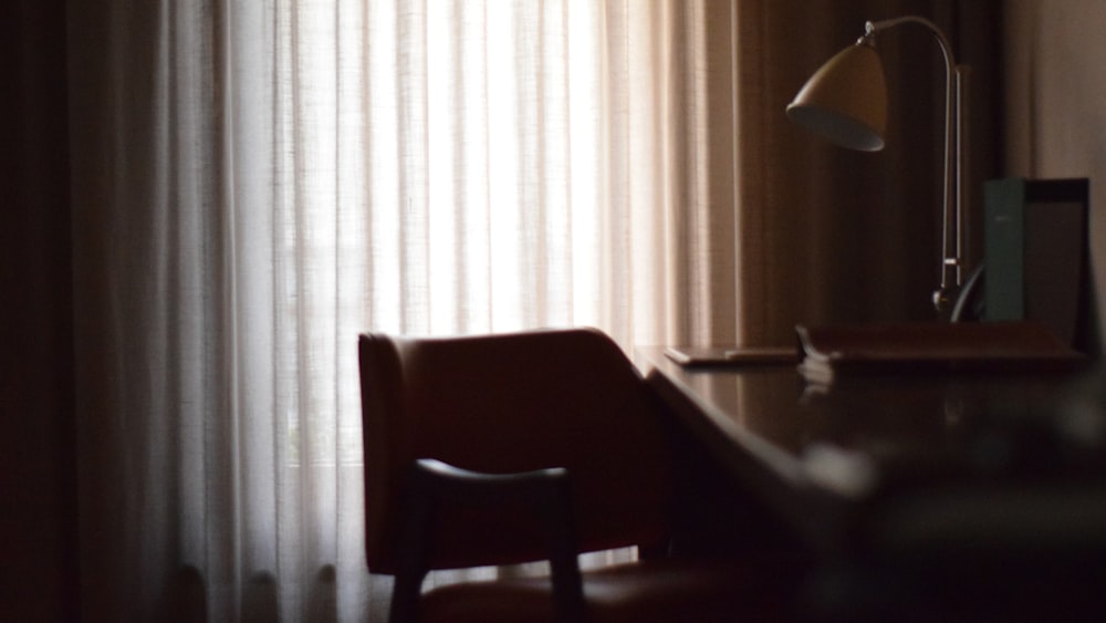 brown wooden chair beside white window curtain