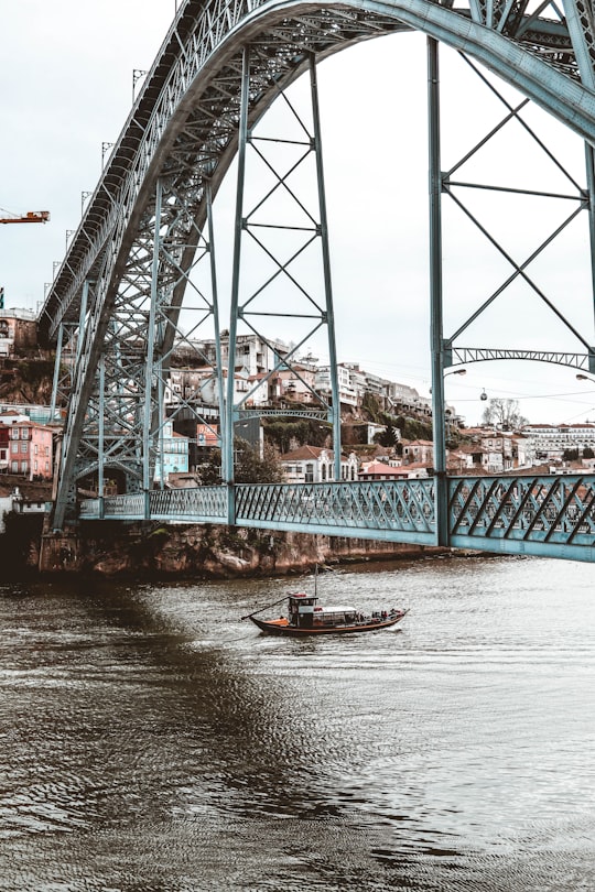 red and white boat on body of water under bridge during daytime in Dom Luís Bridge Portugal