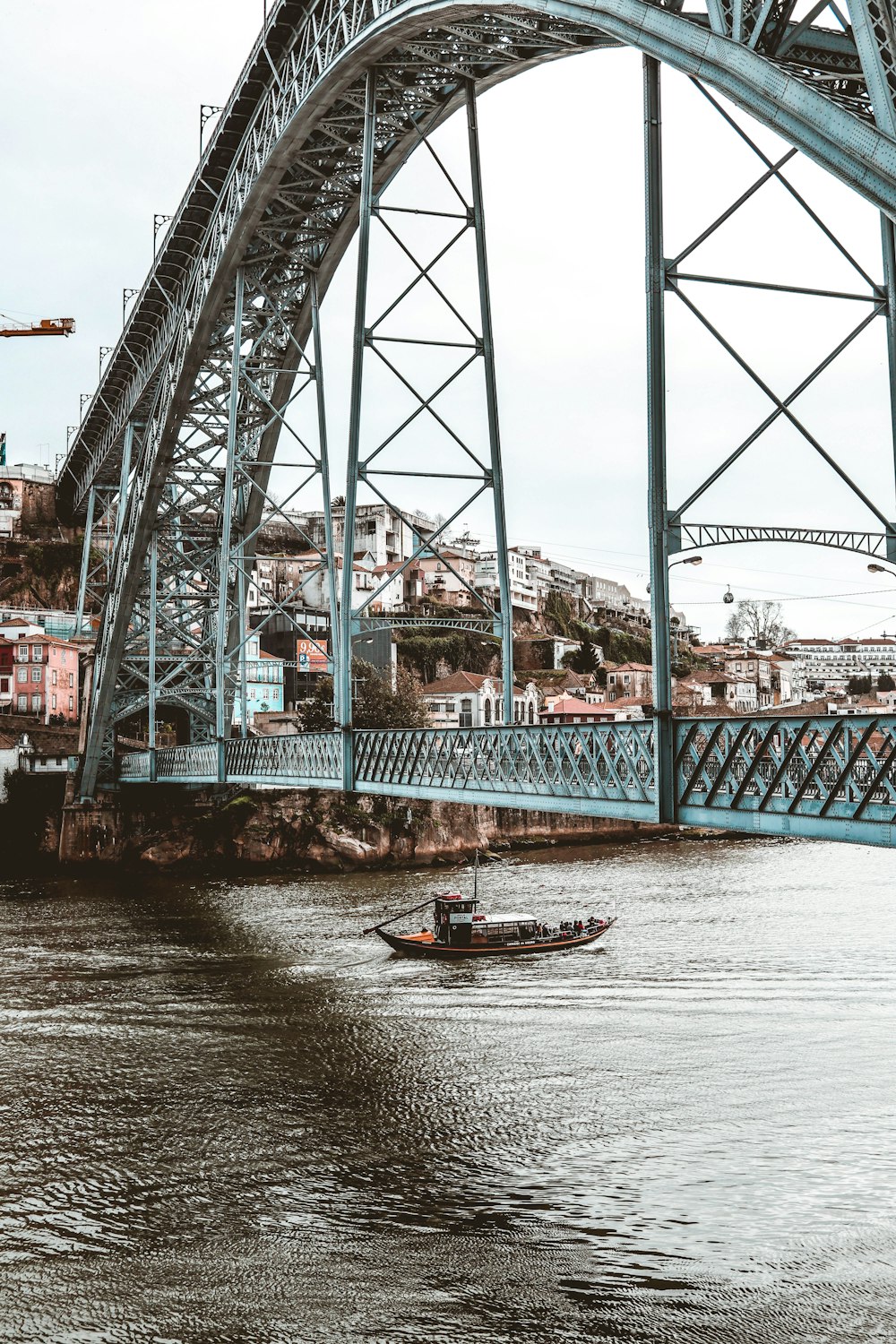 red and white boat on body of water under bridge during daytime