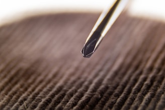 Close-up of hands holding a manual screwdriver with a wooden background.