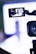 A video camera is focusing on a runway where a fashion show appears to be taking place. The camera's screen displays a person walking down the runway with bright lights and a blurred background.