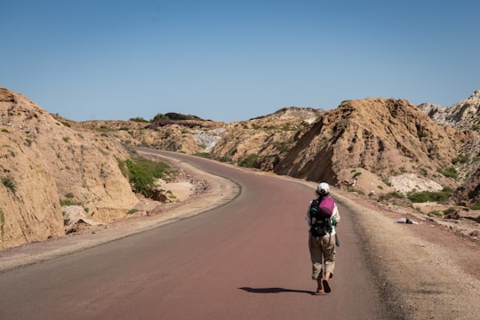 man in black jacket riding on brown horse on brown dirt road during daytime in Hormuz Island Iran