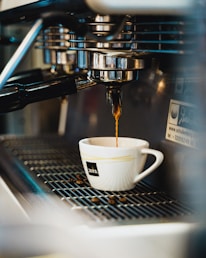 white ceramic cup on silver coffee maker