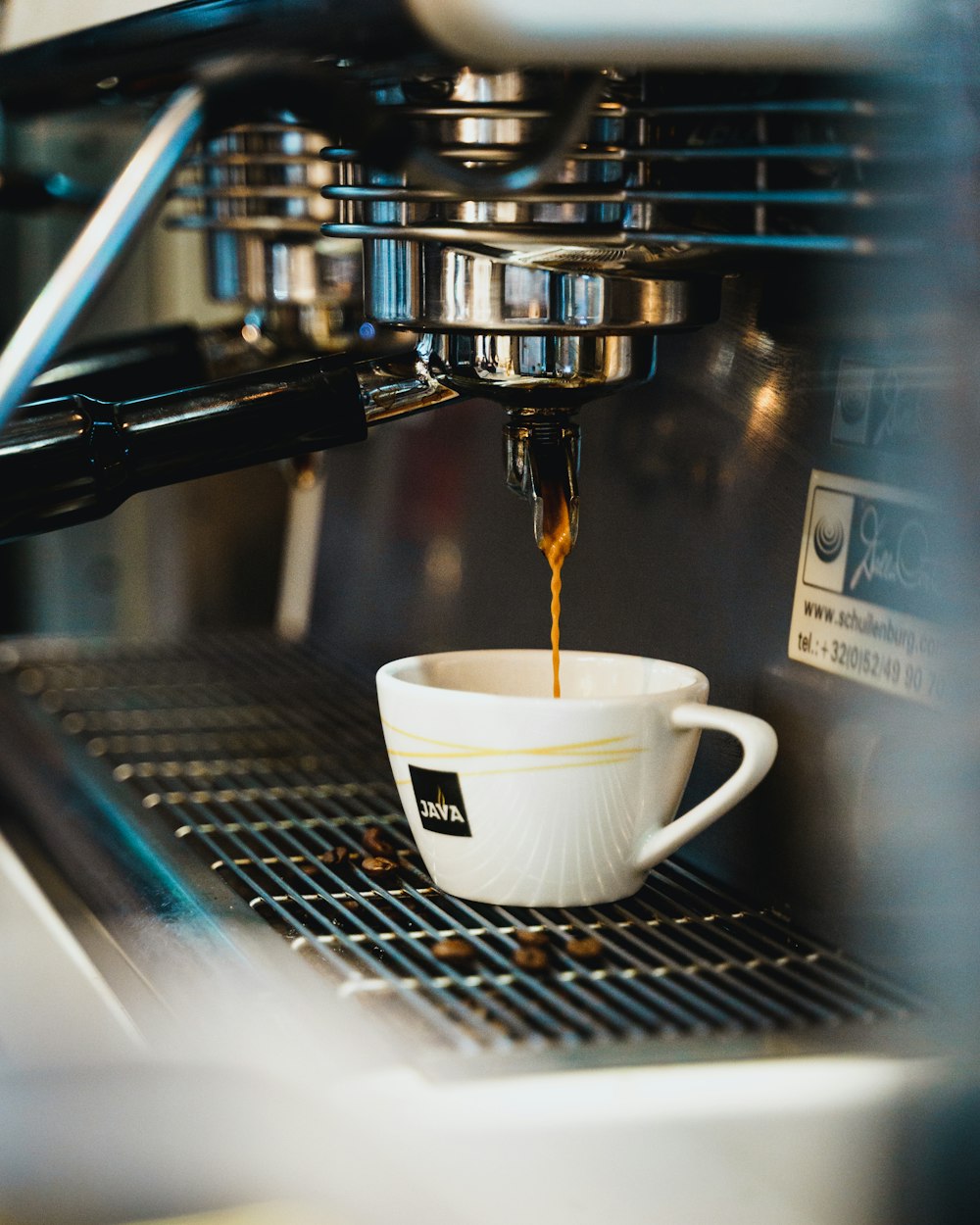 white ceramic cup on silver coffee maker