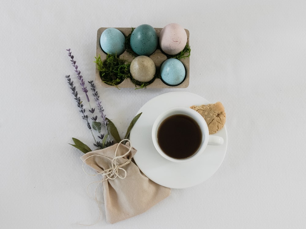 白い陶器の皿に緑と茶色の卵、白い陶器のマグカップとコーヒー