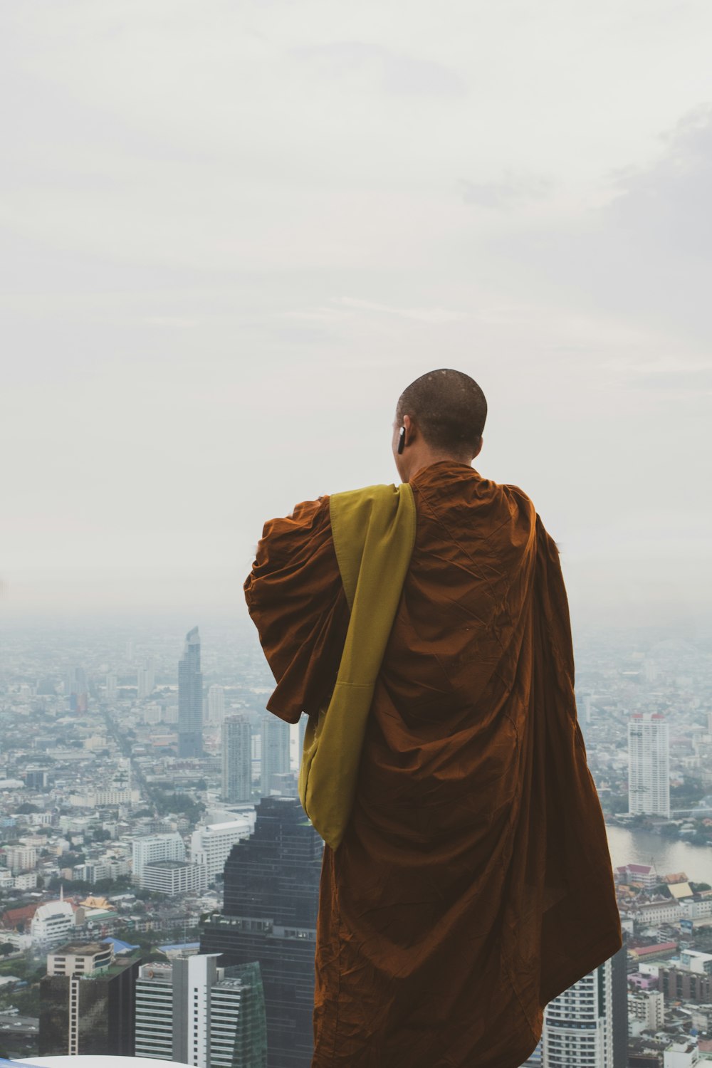 man in brown robe standing on top of building during daytime