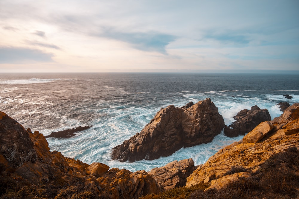 brown rocky mountain beside sea during daytime