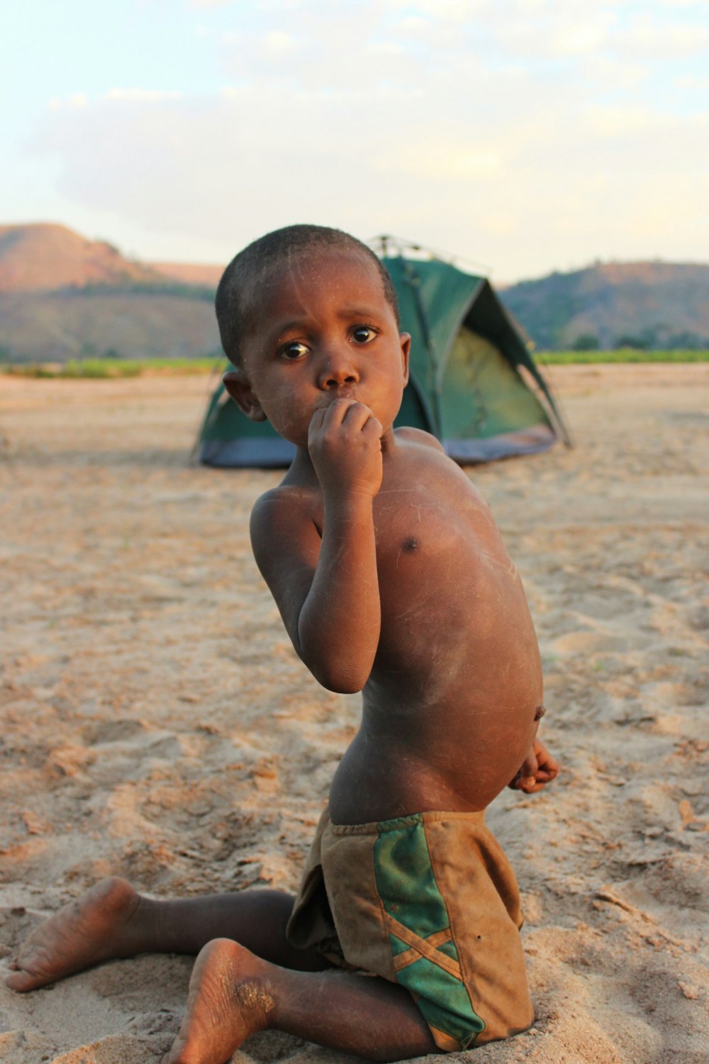 boy in green shorts sitting on sand during daytime