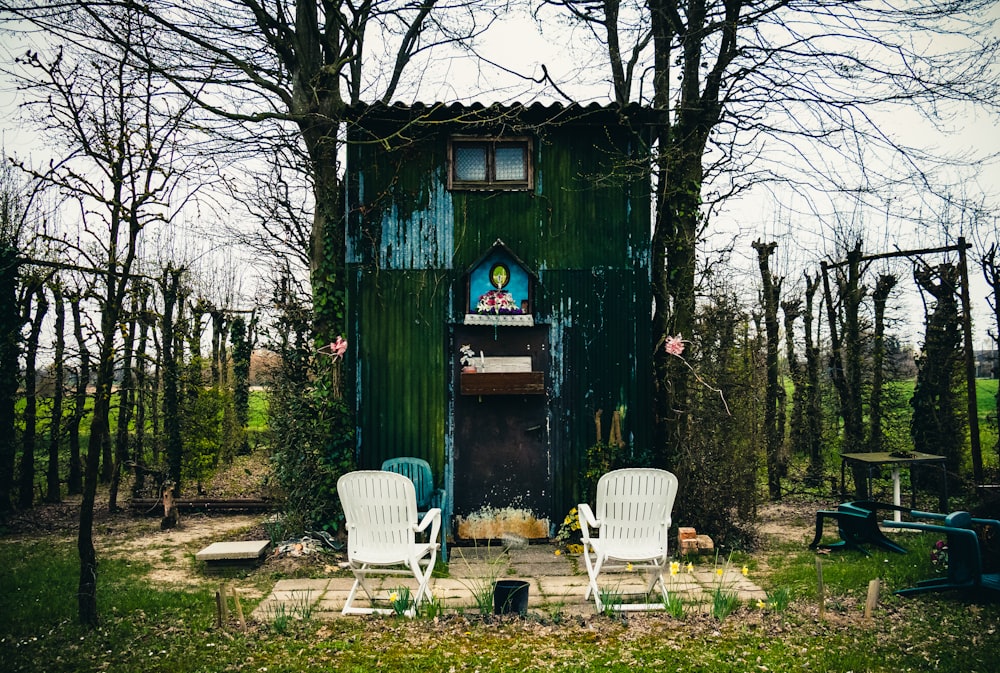 white plastic armchair beside green wooden house
