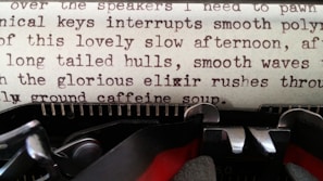 A close-up of a vintage typewriter with a partially typed page of a forbidden age gap romance story, set against a blush fabric background.