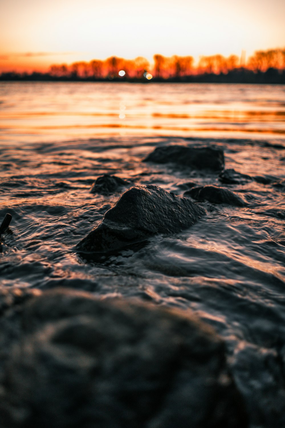 black rock formation on sea during sunset