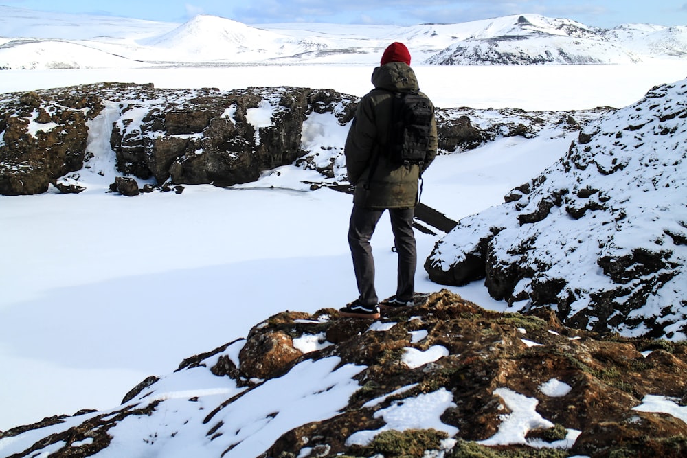 man in black jacket and black pants standing on snow covered ground during daytime