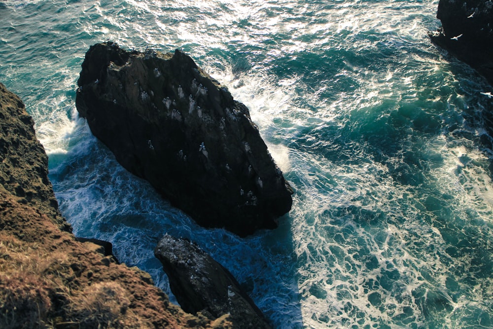 black rock formation on blue sea water during daytime