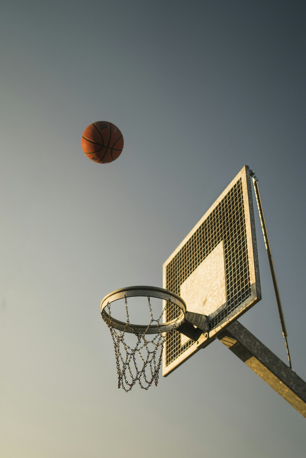 pallacanestro sul canestro da basket sotto il cielo blu durante il giorno