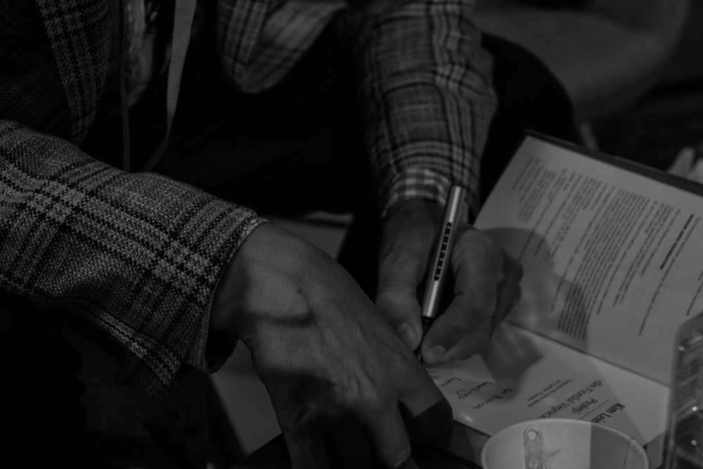 grayscale photo of person writing on paper