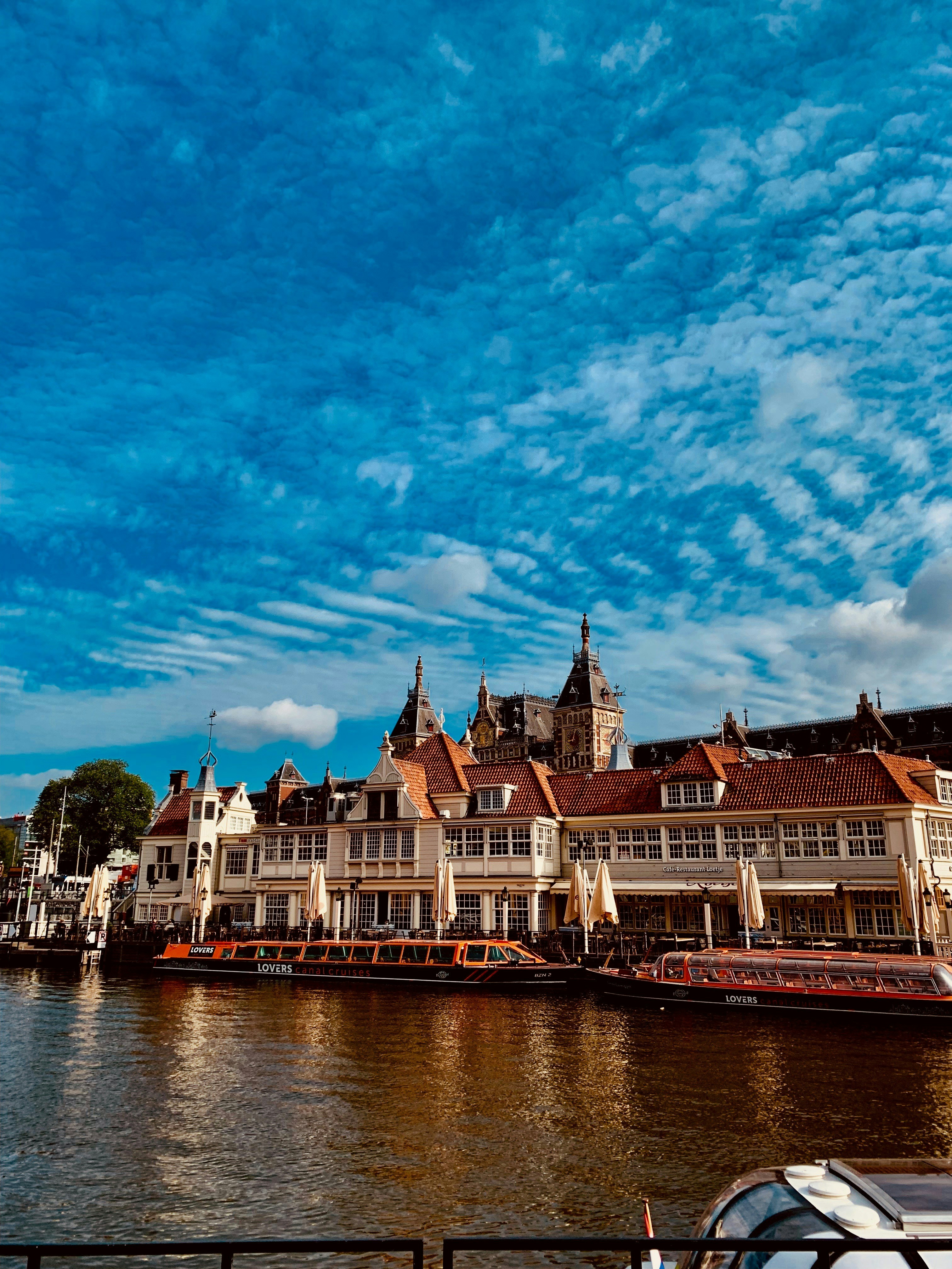 brown and white concrete building near body of water under blue sky during daytime