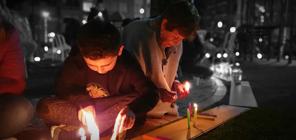 man in brown long sleeve shirt playing with lighted candles