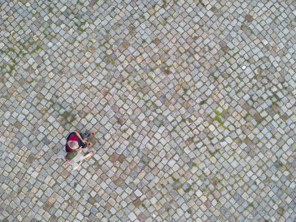 person in black and red shorts sitting on gray concrete floor