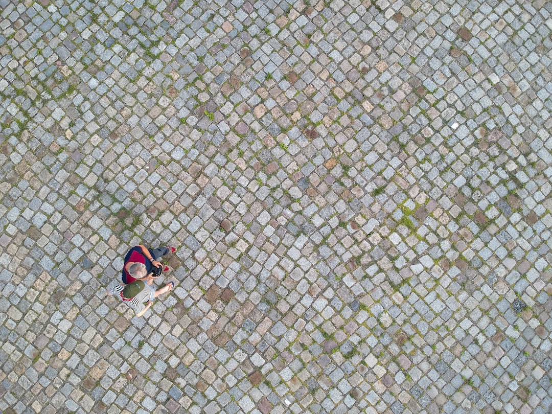person in black and red shorts sitting on gray concrete floor, exploring the drone