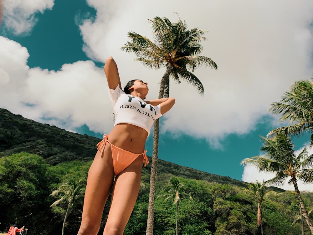 woman in white bikini standing on green grass field during daytime