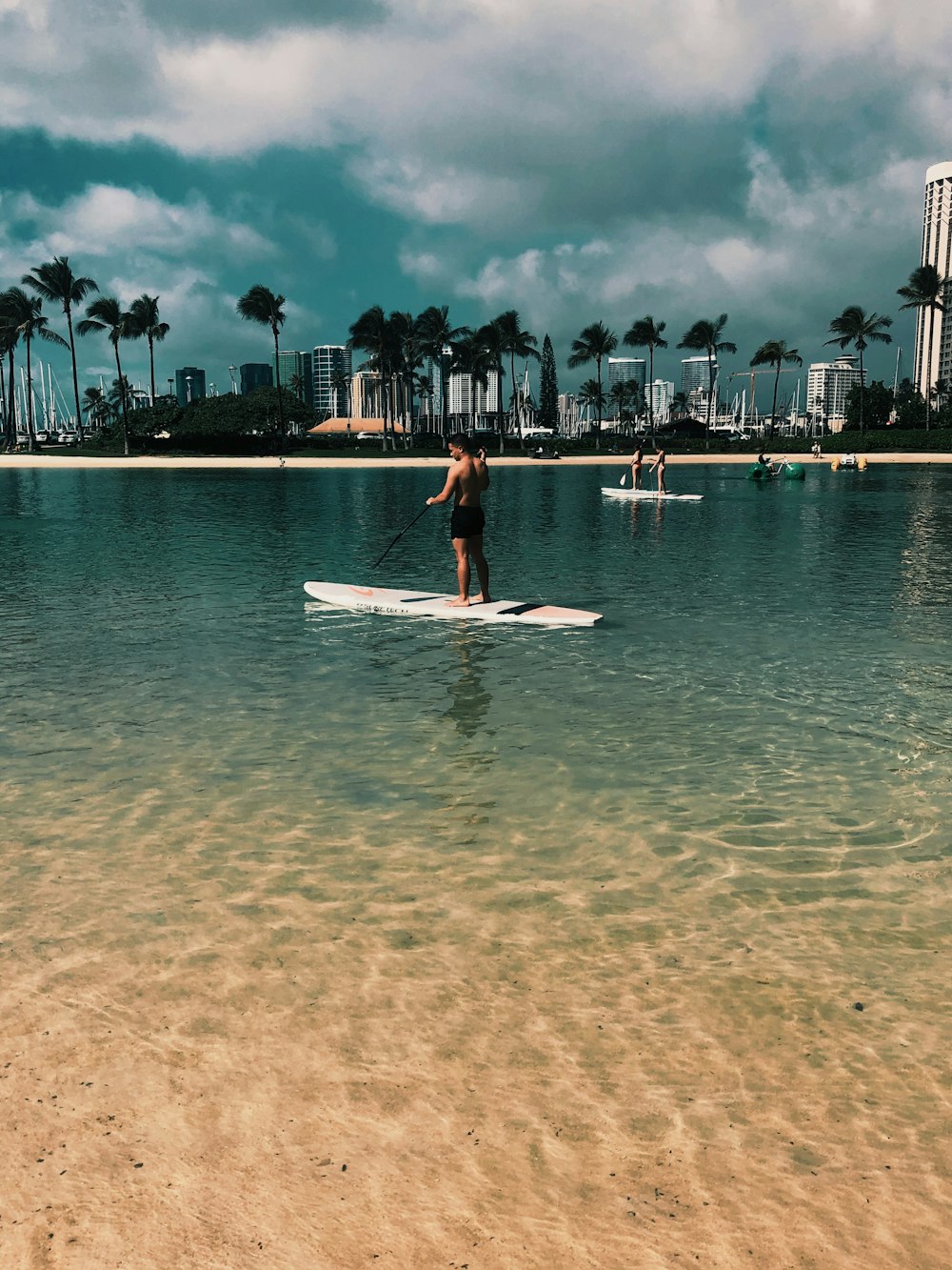 woman in red dress standing on white surfboard on beach during daytime