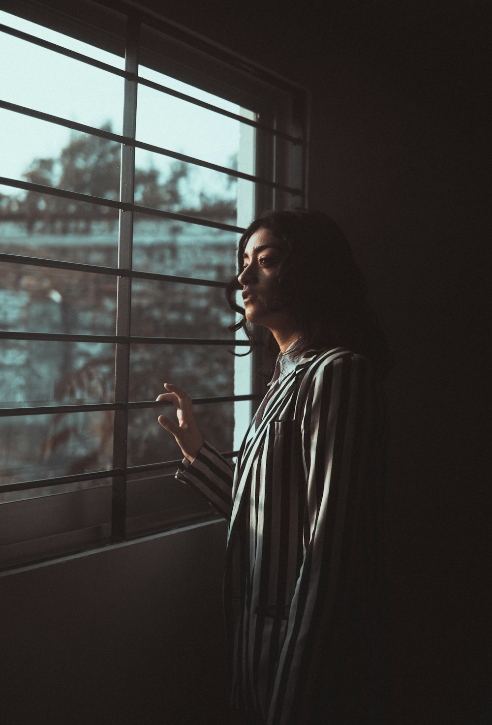 woman in black and white striped long sleeve shirt standing near window