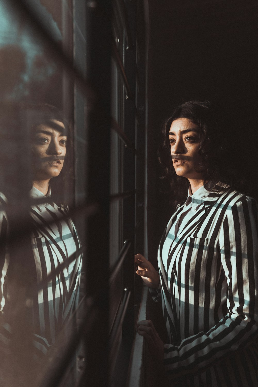 woman in green and white plaid button up shirt standing beside black metal gate