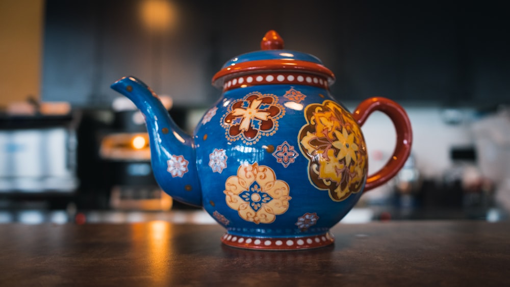 blue and brown ceramic teapot on brown wooden table