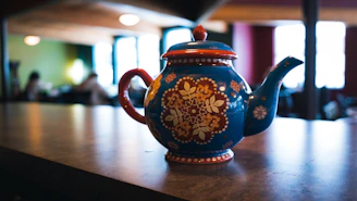 Close-up of a colorful stoneware teapot with a cozy knitted backdrop.