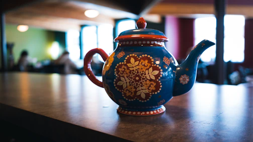Close-up of a colorful stoneware teapot with a cozy knitted backdrop.